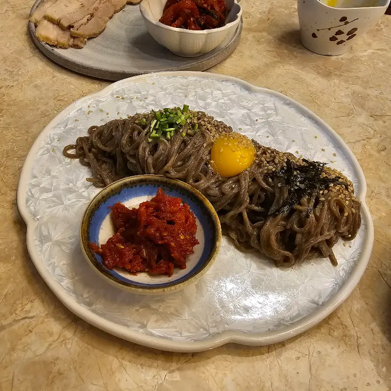 들깨 막국수와 보쌈, 쭈꾸미 볶음이 함께 있는 모습