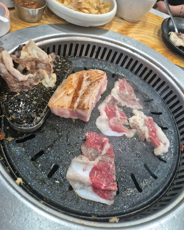 맛찬들 하남미사점 불판 위에 올려진 삼겹살, 목살, 멜젓