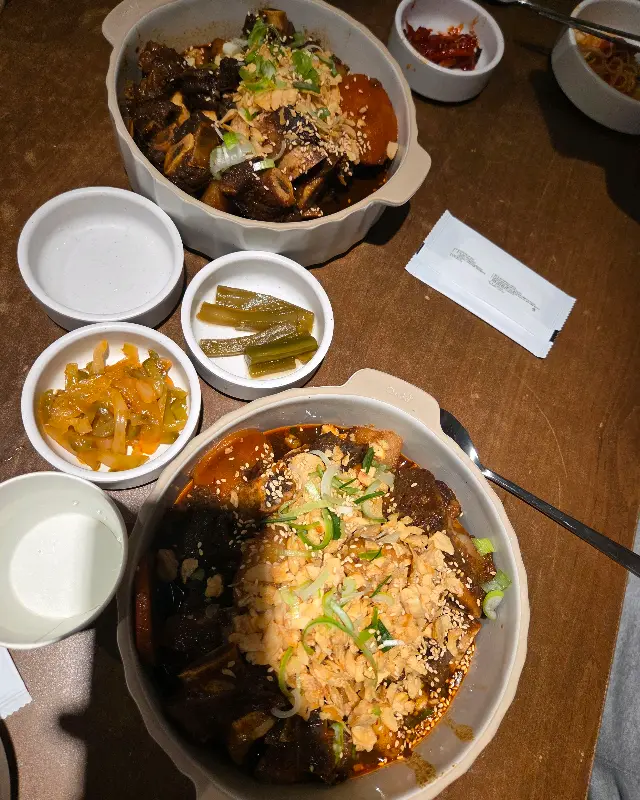 소갈비찜이 놋그릇에 담겨져 있고, 주변에 다양한 곁들임 반찬들이 놓여있다.