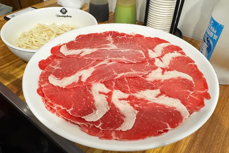 테이블 위에 놓인 붉은 빛깔의 소고기 접시