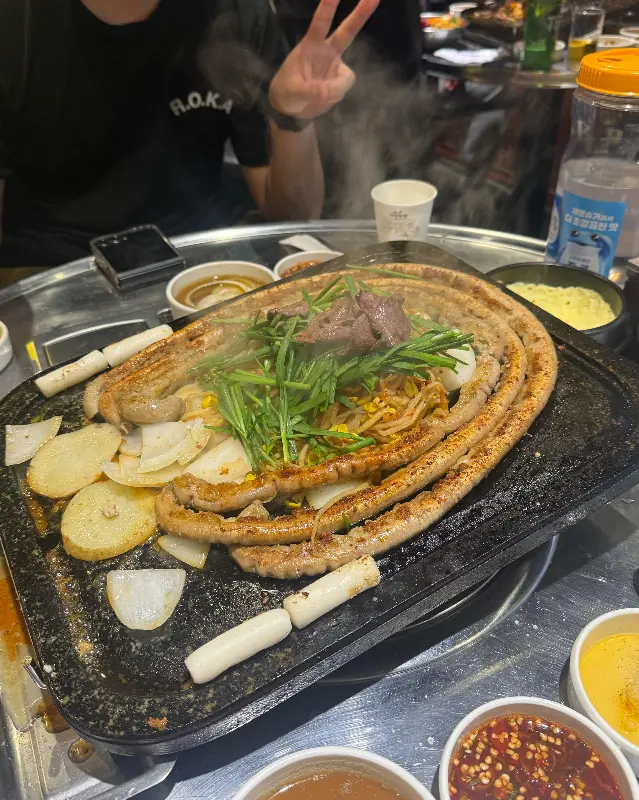 돌판 위에 구워진 대창과 김치, 콩나물이 함께 놓여 있는 모습