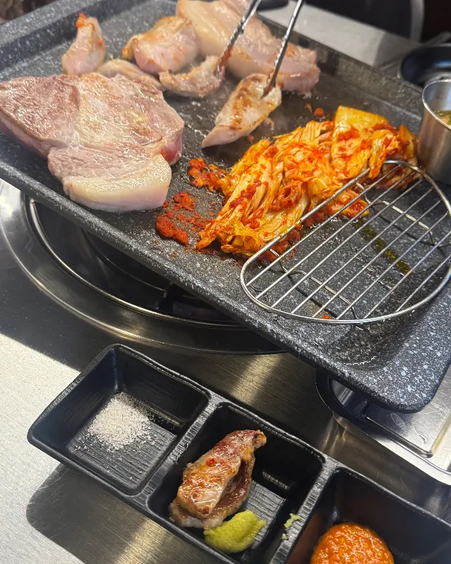 푸줏간 정육식당 불판 위에서 익어가는 삼겹살과 김치