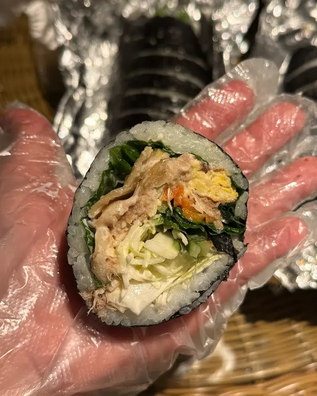 손으로 들고 찍은 참치 김밥 단면 사진