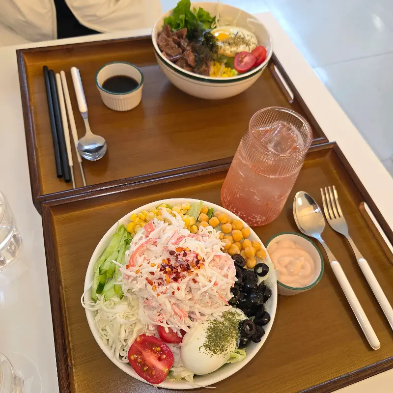 크랩 샐러드와 스테이크 덮밥이 나무 트레이에 담겨 있는 모습