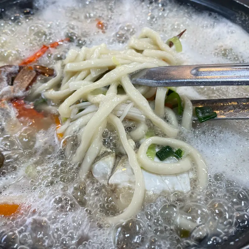 해산물이 가득 들어간 해물칼국수의 면을 집어 올리는 모습