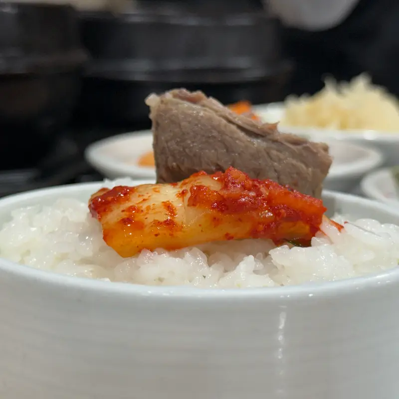 밥 위에 갈비와 깍두기를 올려 먹는 모습