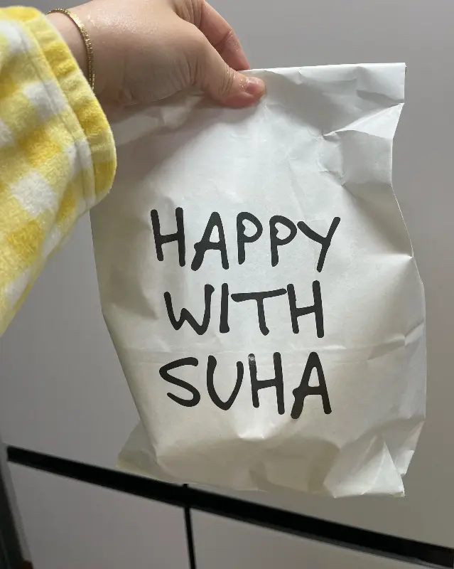 HAPPY WITH SUHA 문구가 적힌 종이봉투