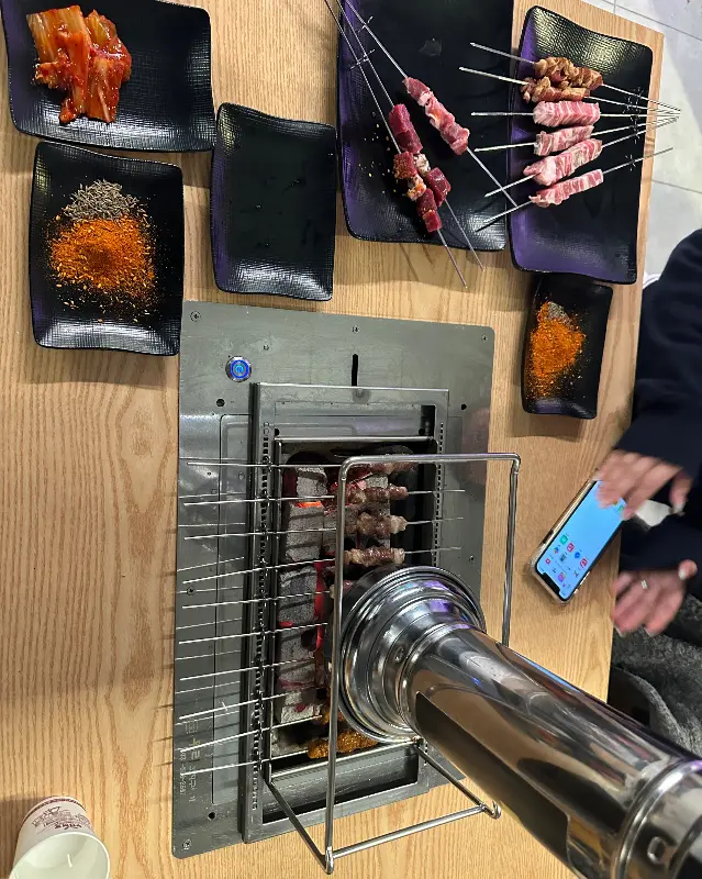 테이블 가득 차려진 양꼬치와 쯔란, 김치 등의 반찬들