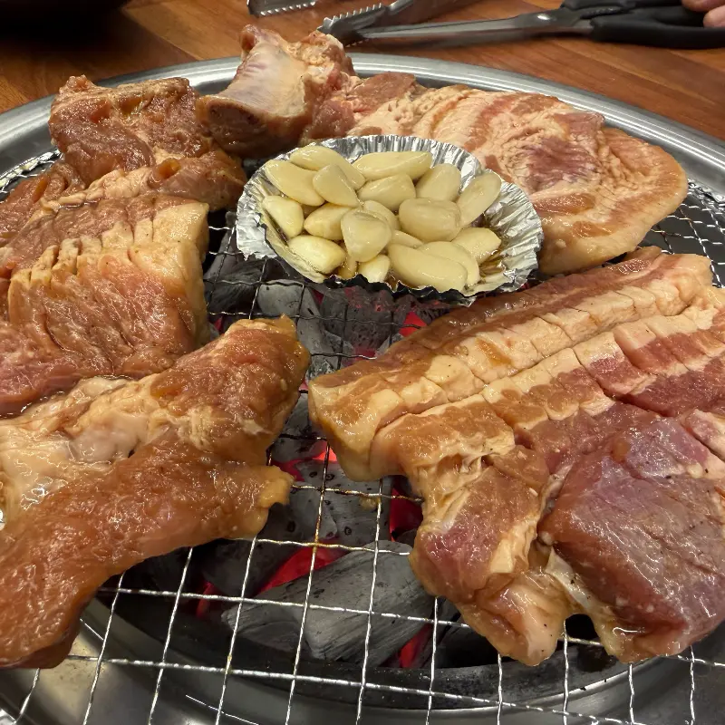 숯불 위에서 익어가는 돼지갈비와 마늘