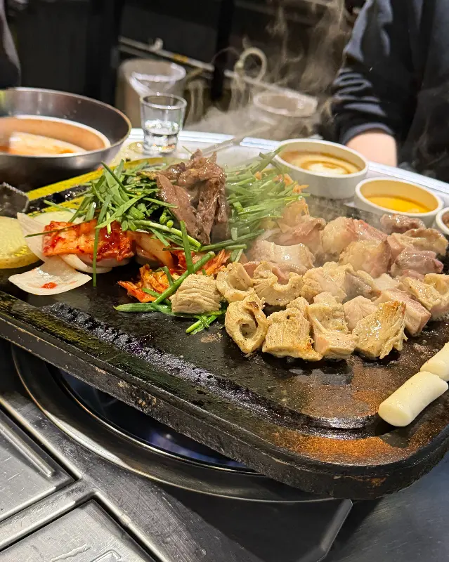 돌판 위에 곱창, 대창, 염통, 김치, 콩나물 등이 푸짐하게 올려져 있는 모습