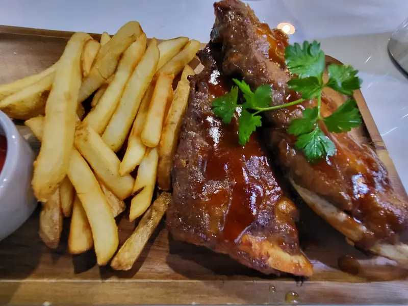 바베큐 폭립과 감자튀김이 함께 담긴 나무 도마 사진