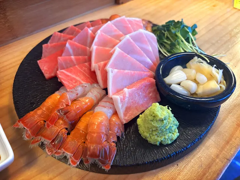 검은색 쟁반 위에 숙성 참치회와 딱새우회가 놓여 있다. 참치는 붉은 빛깔을 뽐내고 있고, 딱새우는 주황색 껍질이 윤기를 자랑한다.