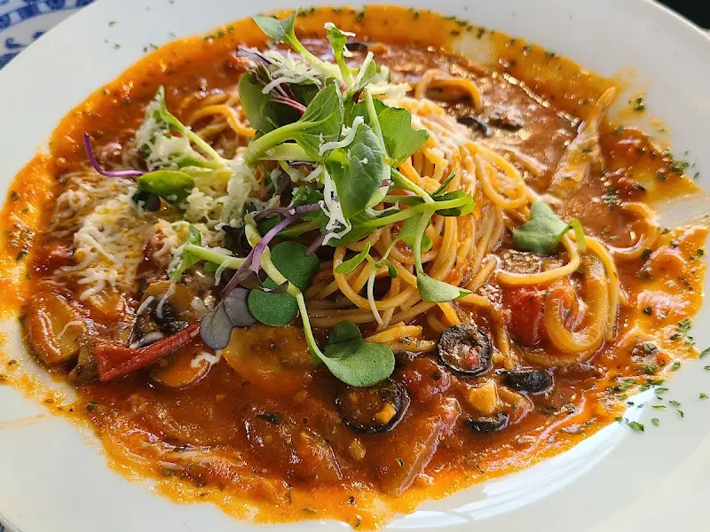 토마토 파스타 위로 잎채소가 얹어진 모습