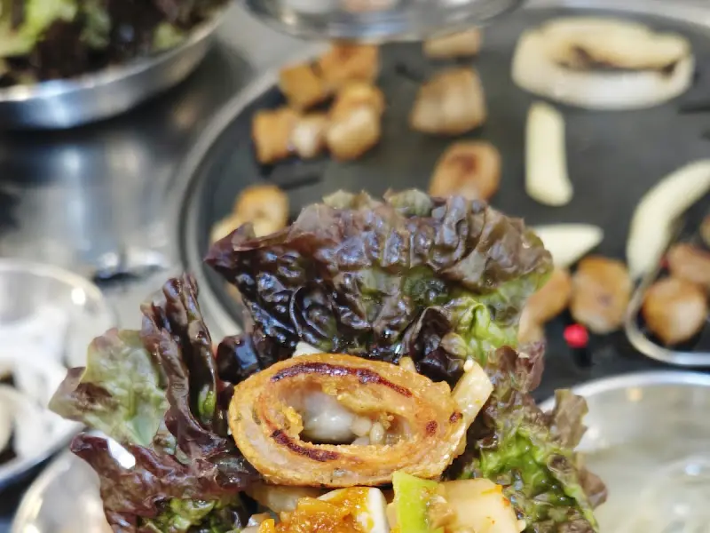 맛있게 구워진 막창을 쌈에 싸서 먹는 모습