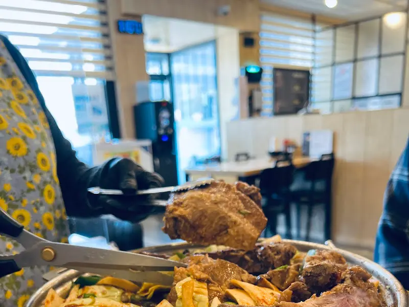 검은 장갑을 낀 직원이 집게와 가위를 이용해 용머리 갈비찜을 손질하는 모습