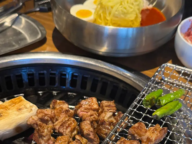 숯불 위에서 구워지는 온겹살과 통 버섯, 그리고 먹음직스러운 비빔국수