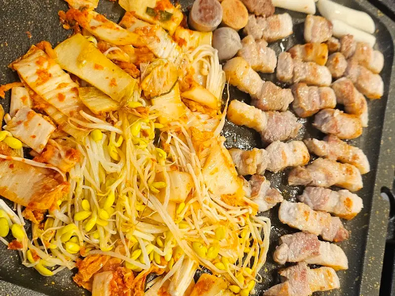 돌판 가득한 삼겹살과 곁들임 재료들