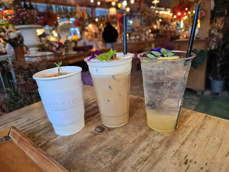 테이블 위에 놓인 음료 세 잔. 모두 꽃으로 장식되어 있다.