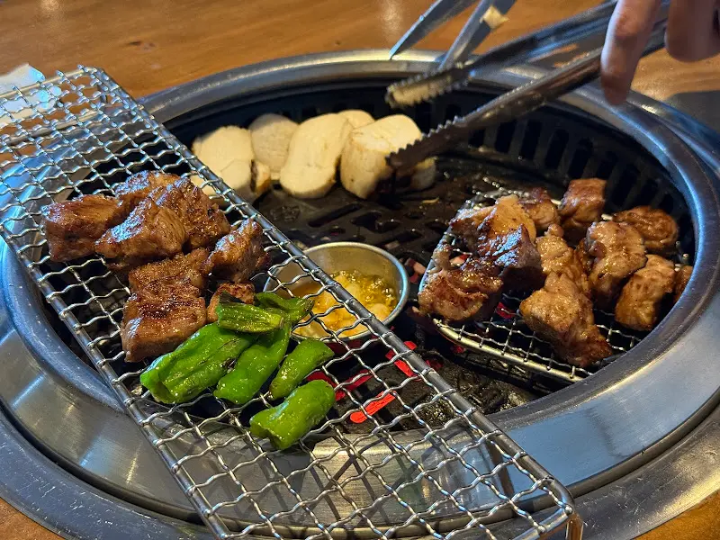 숯불 위에서 맛있게 구워지고 있는 직각 목살과 꽈리고추, 통 버섯
