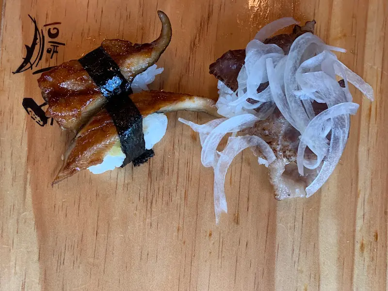 장어 초밥과 소고기 초밥이 나무 도마 위에 나란히 놓여 있는 모습