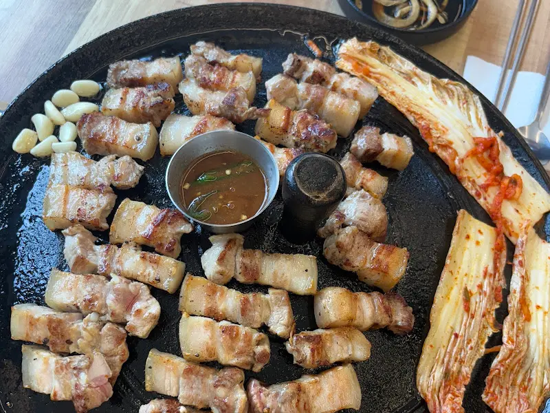 솥뚜껑에 구워지는 미박삼겹살과 김치, 마늘