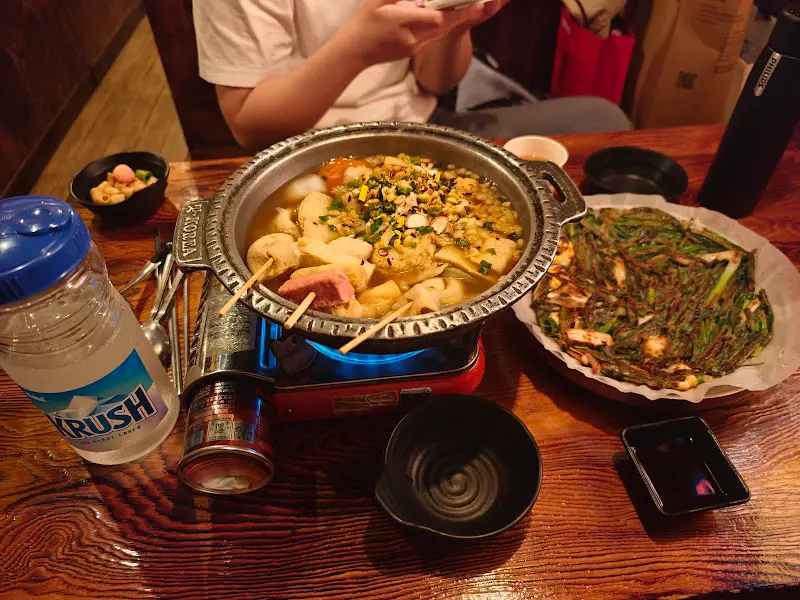 테이블 위 끓고 있는 김치 오뎅탕과 해물파전