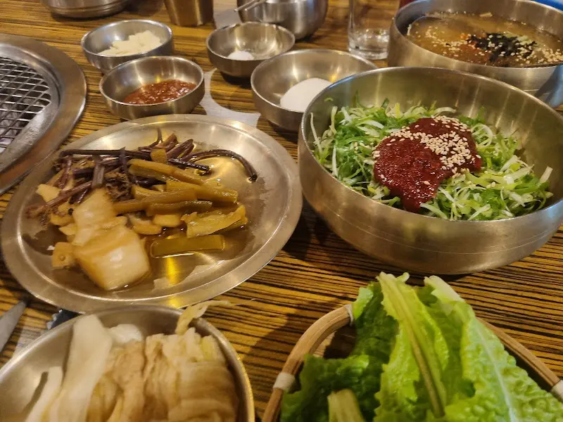 다채로운 곁들임 찬들이 정갈하게 담겨 테이블 위에 놓여있는 모습