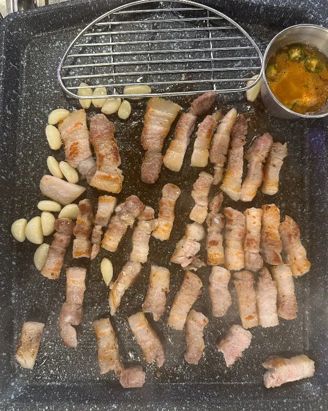 푸줏간 정육식당 불판 가득 올려진 삼겹살과 마늘