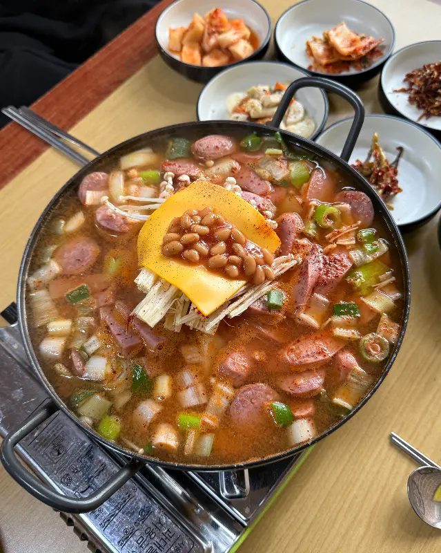 보글보글 끓고 있는 부대찌개의 모습이 담겨 있다. 다양한 종류의 햄과 소시지가 푸짐하게 들어가 있다.