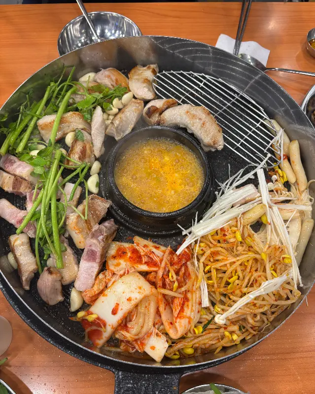 솥뚜껑 위 삼겹살, 김치, 콩나물, 미나리, 팽이버섯