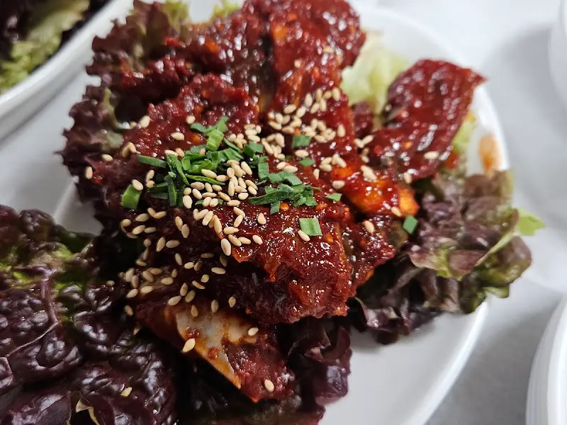 양념게장이 붉은 양념에 버무려져 접시에 담겨 있다. 깨가 뿌려져 있다.