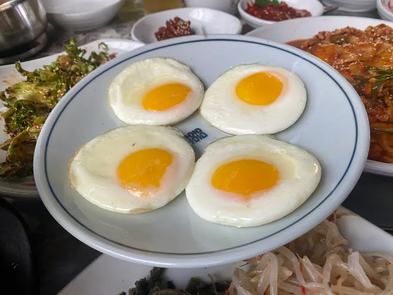 반숙으로 구워진 계란 후라이 네 개가 담겨 있는 접시