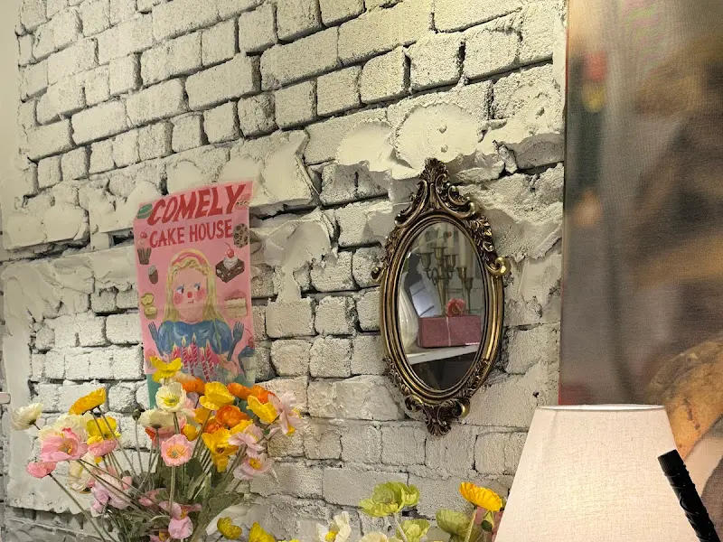 벽돌 벽에 장식된 앤티크한 거울과 아기자기한 그림, 꽃 장식