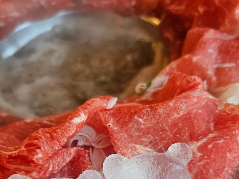 테이블 중앙의 육수를 중심으로 얇게 썰린 소고기가 가득 담긴 접시