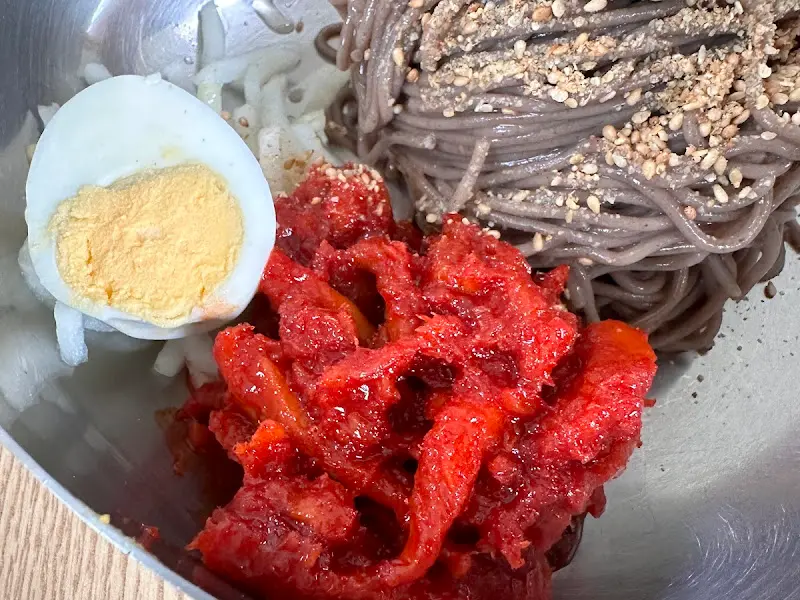 막국수 면과 양념, 계란 고명이 어우러진 모습