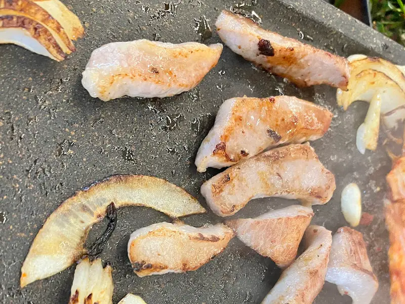불판 위에서 맛있게 익어가는 삼겹살과 양파