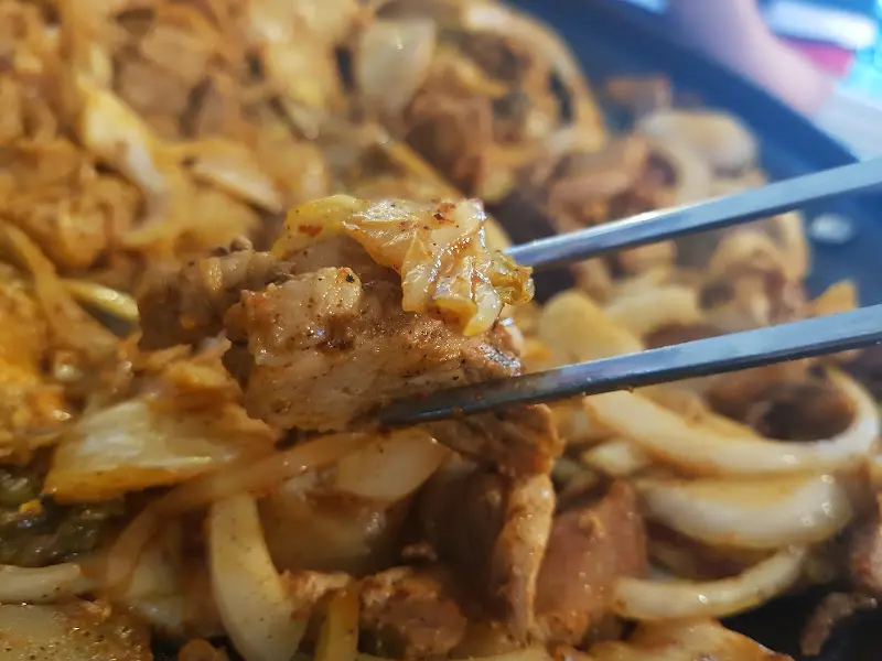 젓가락으로 돼지고기와 김치를 집는 모습