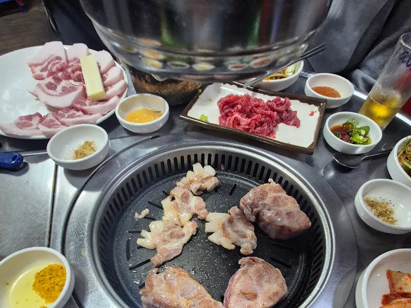 불판 위에 고기와 치즈, 다양한 밑반찬이 놓여있는 모습