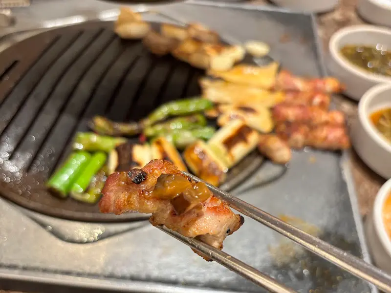 잘 구워진 삼겹살을 젓가락으로 집어 올린 모습