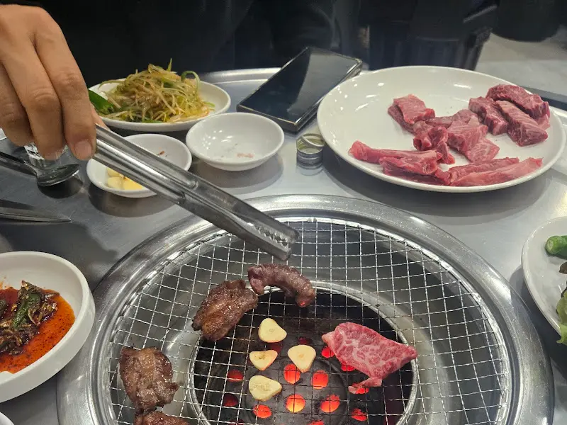 숯불 위에 구워진 한우를 젓가락으로 집는 모습