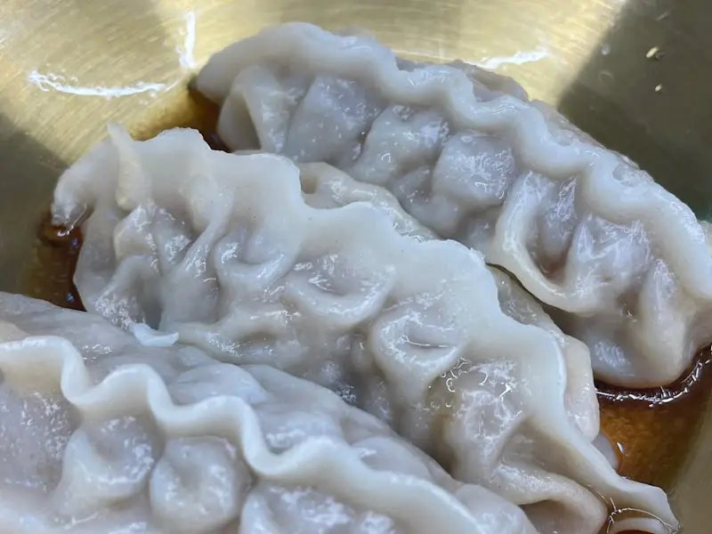 촉촉하게 간장 양념이 뿌려진 갈비만두 세 개가 접시에 담겨 있다.