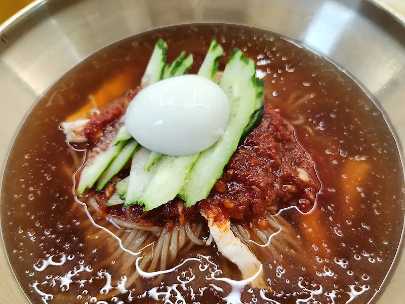 물밀면의 클로즈업 사진. 면과 양념, 오이, 삶은 계란이 조화롭게 담겨 있다.