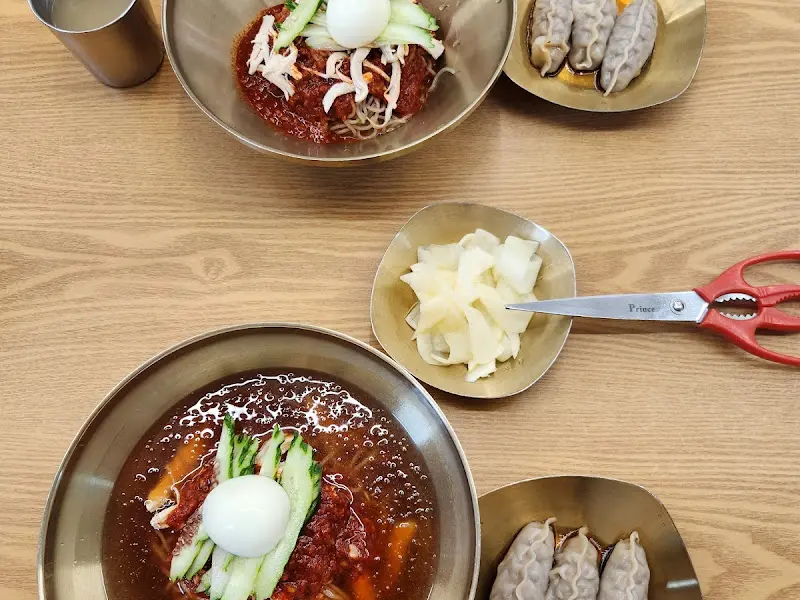 테이블 위에 놓인 물밀면과 비빔밀면, 갈비만두의 모습. 푸짐한 한 상 차림이 인상적이다.