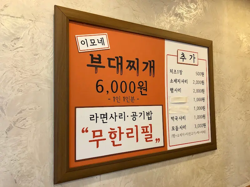 벽에 붙어있는 메뉴판. 부대찌개 가격과 사리 추가 가격이 적혀있다.