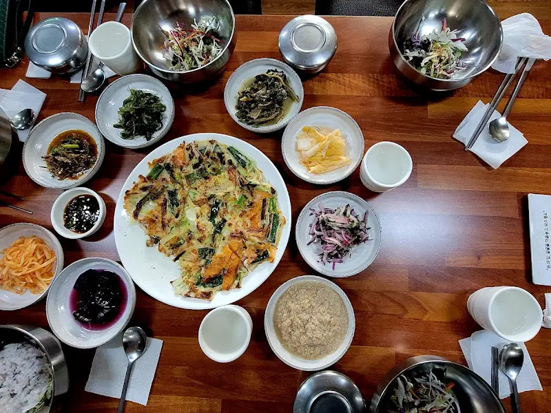 푸짐한 한 상 차림. 파전, 두부, 각종 반찬들이 조화롭게 어우러진다.