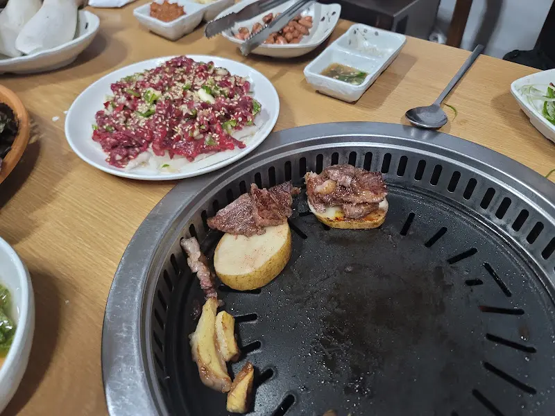 불판 위에 구워지는 소고기와 감자, 버섯