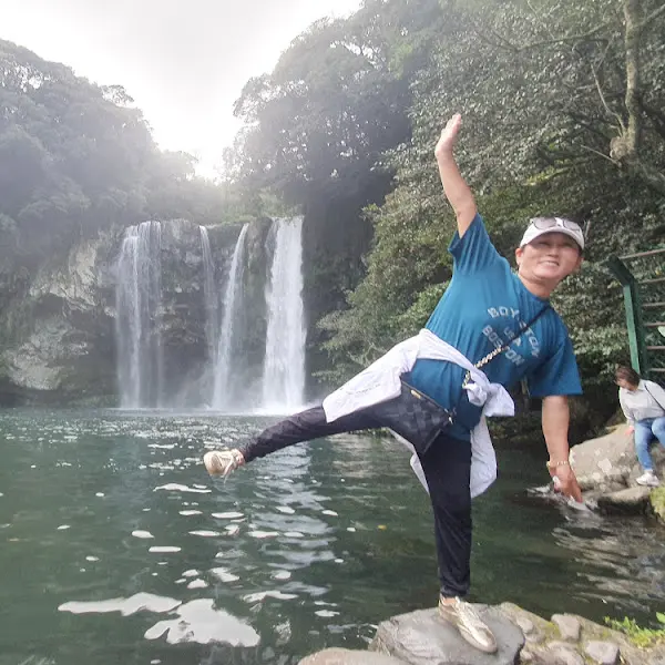 폭포 앞에서 포즈를 취한 사람