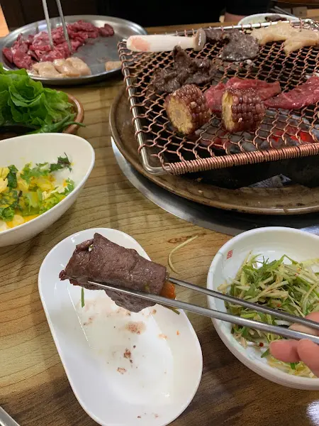 잘 구워진 고기를 젓가락으로 집는 모습