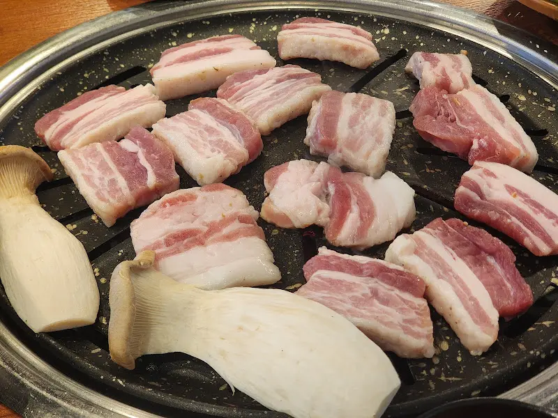 불판 위에 올려진 삼겹살과 새송이버섯