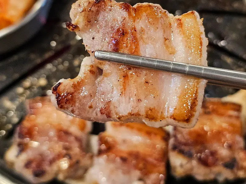 잘 익은 삼겹살을 젓가락으로 집는 모습